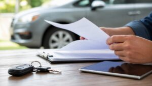 Hands sorting auto loan documents beside car keys