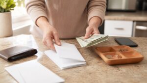 Hands separating blank bill envelopes from spending money