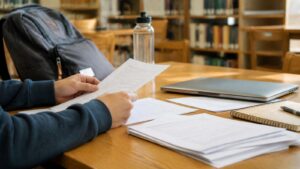 Student hands reviewing blank account paperwork at a study table